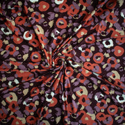 A close-up of Italian Cotton Jersey Warm Abstract Print fabric swirled to demonstrate fabric fullness.