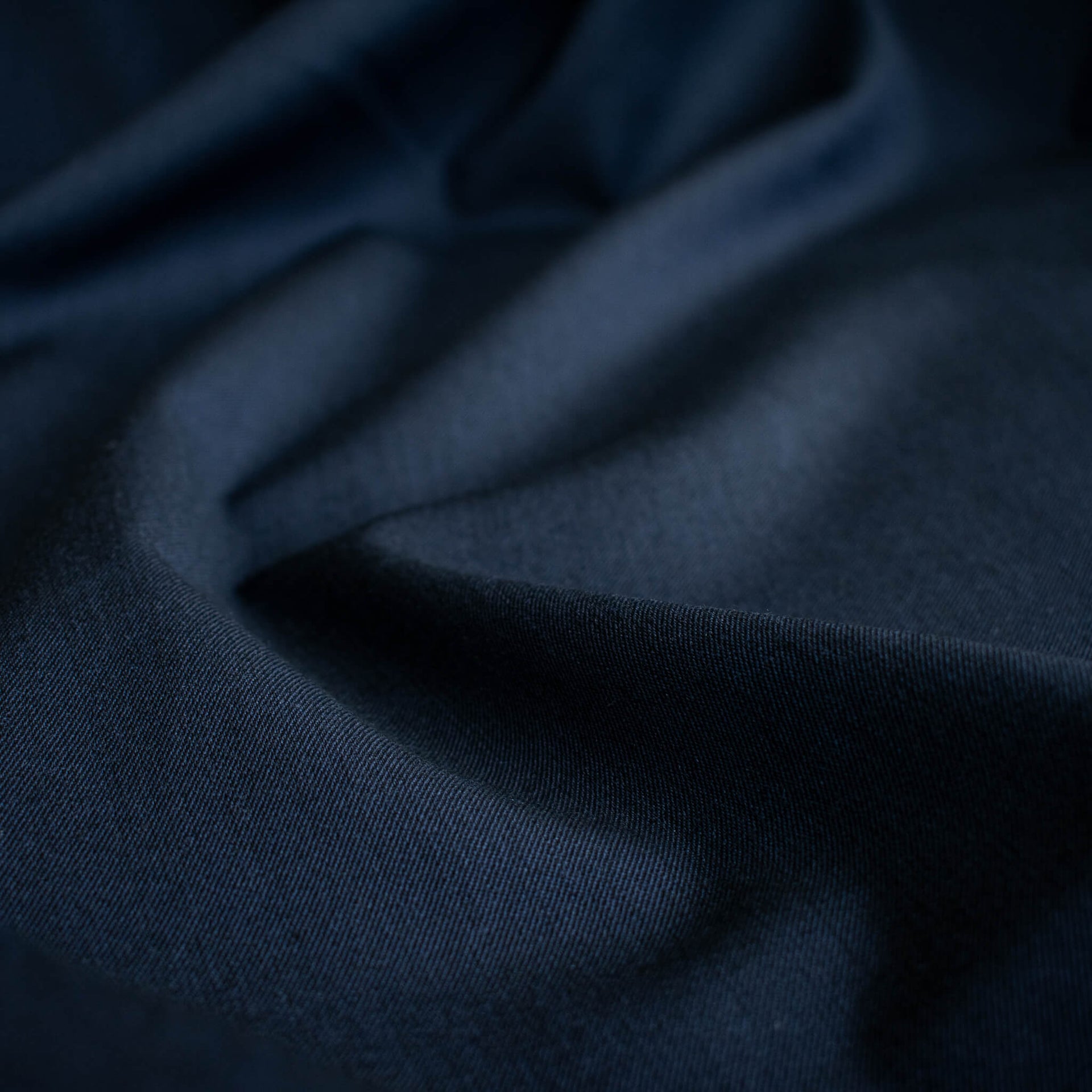 A close-up of draped Couture Italian wool and linen blend navy gabardine fabric  with soft folds 