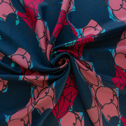 Image of  Italian silk twill fabric by the yard in a modern painterly print draped dress form. Colors are  coral pink, deep red, and turquoise on a dark navy background. Fabric is twirled to demonstrate fullness