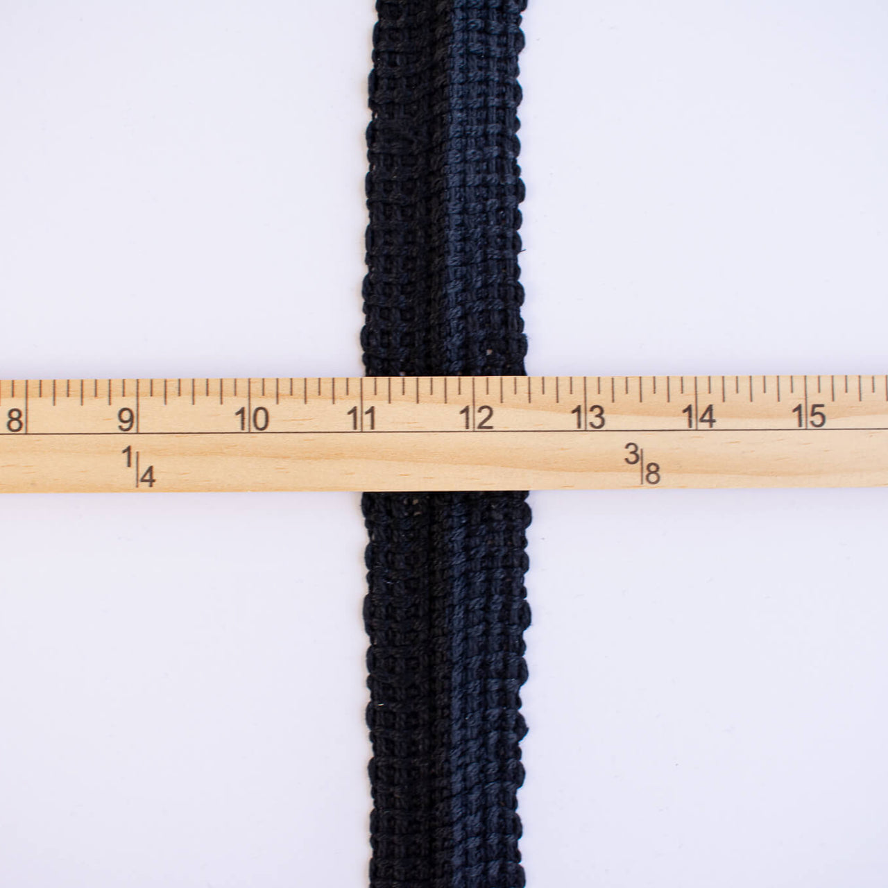 Vintage Foldover Black Braid Cotton Trim is back! This 1 and one-half inch trim can be folded to a sleek five-eighths of an inch creating a perfect clean finish for your sewing project. It also looks gorgeous as a base trim when layering trims for a designer look. Image of flattened trim and ruler to show width