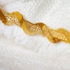 Bring a touch of couture to your project with our vintage gold double scallop trim. You’ll love the irresistible shades of gold scallops as they twist about a core of metallic golden threads. Whether you are embellishing a Classic French Jacket or a dress, this trim will add a timeless sophistication.  Close up photo with boule fabric which is sold seperately.