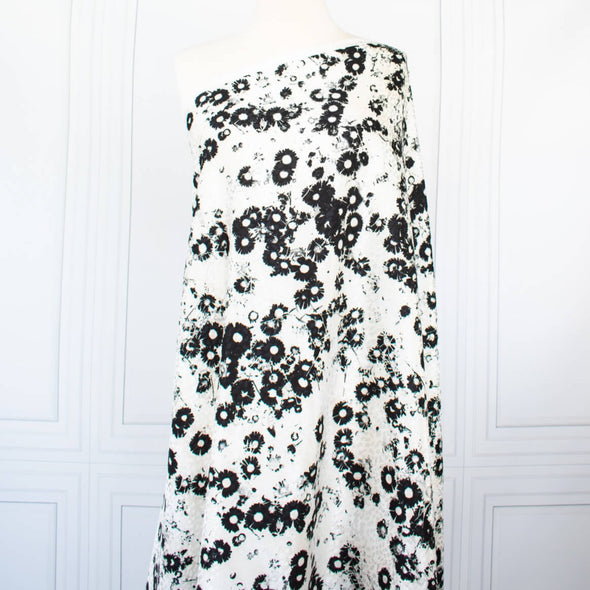 Image on dressform of couture black and creamy white floral Jacquard. This designer deadstock fabric by the yard features a stunning modern black daisy design set against a white shimmery jacquard.