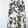 Image of draped couture black and creamy white floral Jacquard. This designer deadstock fabric by the yard features a stunning modern black daisy design set against a white shimmery jacquard.