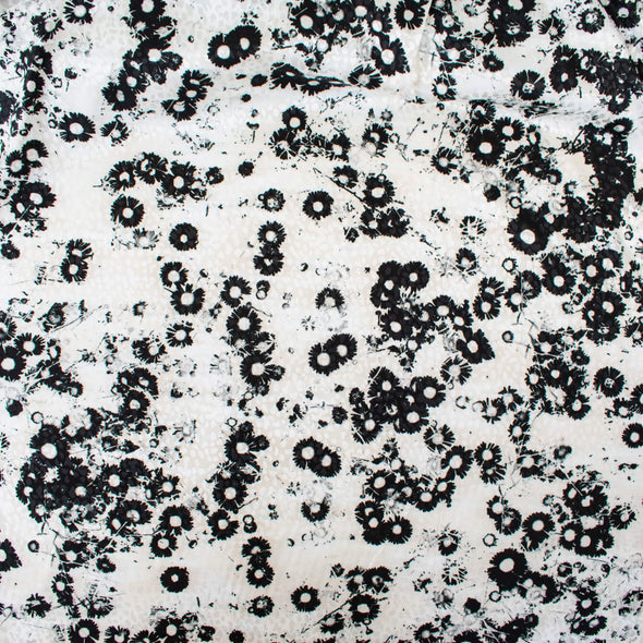 Image of couture black and creamy white floral Jacquard. This designer deadstock fabric by the yard features a stunning modern black daisy design set against a white shimmery jacquard.