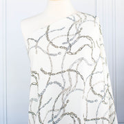 Famous Designer Chain Print Viscose Crepe Faille fabric by the yard. Chain links of tan and grey play upon an ivory background creating a whimsical yet sophisticated look. Slightly translucent with a lightly textured hand, this would make up gorgeous blouse or dress! Image of fabric on dressform.