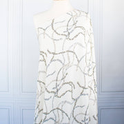 Famous Designer Chain Print Viscose Crepe Faille fabric by the yard. Chain links of tan and grey play upon an ivory background creating a whimsical yet sophisticated look. Slightly translucent with a lightly textured hand, this would make up gorgeous blouse or dress! Image of fabric on dressform.