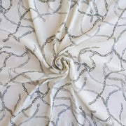 Famous Designer Chain Print Viscose Crepe Faille fabric by the yard. Chain links of tan and grey play upon an ivory background creating a whimsical yet sophisticated look. Slightly translucent with a lightly textured hand, this would make up gorgeous blouse or dress! Image of fabric fullness.