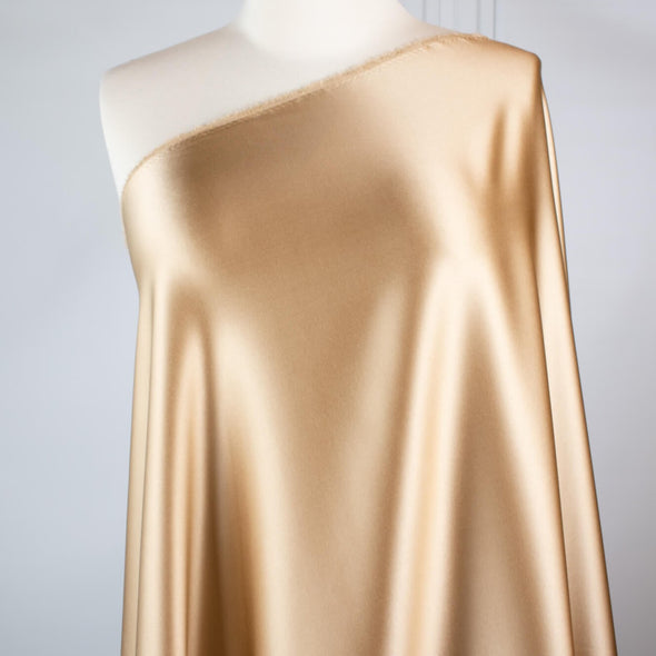 Feel special with a bit of "Shimmer"!  Our designer silk charmeuse in a lovely honey color with a hint of stretch will fancy up your outfit!  Create a gorgeous charmeuse camisole top or go for the popular bias-cut dress or skirt.  And don’t forget, that bit of stretch is perfect if you are lining a French Jacket or just want a bit of extra comfort in your silk. Image of fabric draped on form.