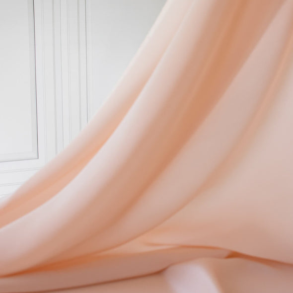 Universally flattering, this 100% Silk Crepe de Chine in a soft coral pink is such a versatile color. It's fluid drape is perfect for your next blouse or dress! Photo of fabric drape.