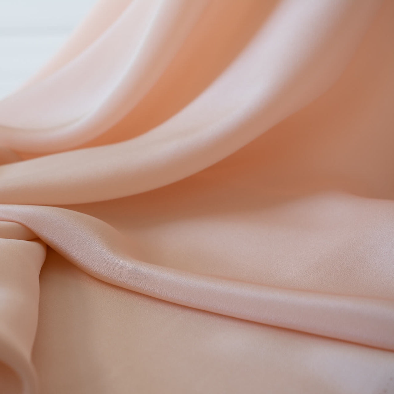 Universally flattering, this 100% Silk Crepe de Chine in a soft coral pink is such a versatile color. It's fluid drape is perfect for your next blouse or dress! Photo. of fabric drape.