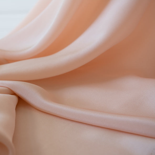 Universally flattering, this 100% Silk Crepe de Chine in a soft coral pink is such a versatile color. It's fluid drape is perfect for your next blouse or dress! Photo. of fabric drape.