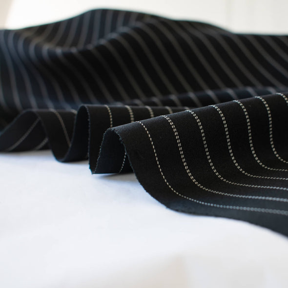 Gorgeous Couture Designer 4-Ply Silk Black with a white vertical double pinstripe, this premium medium weight silk has a soft sheen and gentle drape. A fine smooth hand feels buttery on the skin, perfect for a wide leg pant, vest, jacket or dress! Close up image of selvedge.