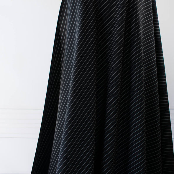 Gorgeous Couture Designer 4-Ply Silk Black with a white vertical double pinstripe, this premium medium weight silk has a soft sheen and gentle drape. A fine smooth hand feels buttery on the skin, perfect for a wide leg pant, vest, jacket or dress! Image of fabric drape.