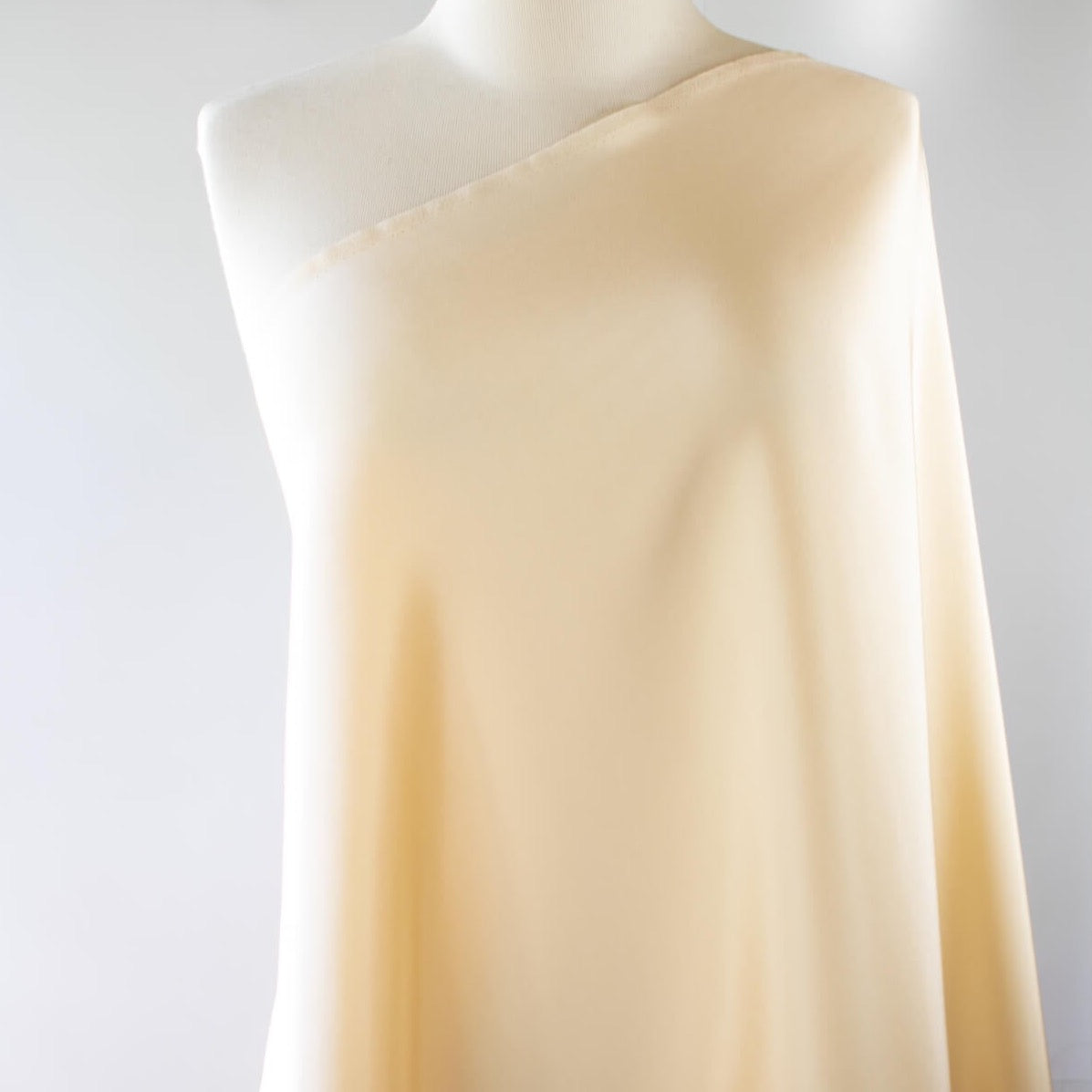 Couture Designer 4-Ply Silk in an ivory buttercream is a premium medium weight silk and is so glamorous! Luxurious and elegant with a soft sheen and gentle drape. A fine smooth hand feels buttery on the skin, perfect for draped, fitted, or fuller styles perhaps a wide leg pant, vest, jacket, or dress!  Image of fabric draped on dressform.