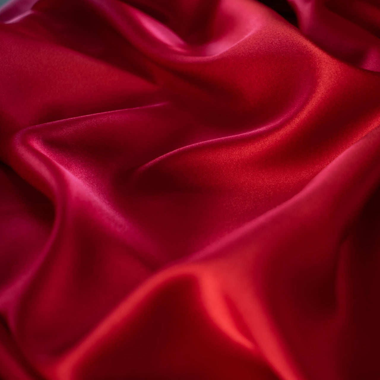 Enjoy the luxury of stretch silk charmeuse in scarlet. Designer deadstock originally from a New York couture designer! You can enjoy the silkiness of a 96 % silk and 4% lycra in a easy to work with 54 inch width for one of your fancy frocks. A popular fabric for creating fluid bias cut garments and luxurious lining to your special pieces like the French Jacket. Close up photo of fabric luster.