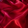 Enjoy the luxury of stretch silk charmeuse in scarlet. Designer deadstock originally from a New York couture designer! You can enjoy the silkiness of a 96 % silk and 4% lycra in a easy to work with 54 inch width for one of your fancy frocks. A popular fabric for creating fluid bias cut garments and luxurious lining to your special pieces like the French Jacket. Close up photo of fabric luster.  