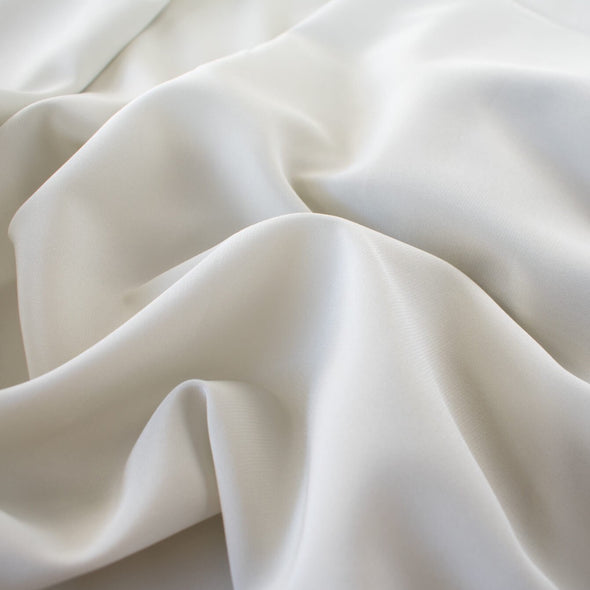 NYC Designer Couture silk/lycra stretch crepe de chine in a fantastic width. The soft, semi-textured fluid drape of this pale grey crepe will create a lovely dress or top for your next sewing adventure. Close up photo.