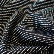 Luxurious designer suiting in black with a white and gold metallic running stitch. Take sophistication up a notch in this gorgeous wool blend with a soft and supple hand. Perfect for a glamorous tailored suit or jacket. Image of running stitch side of fabric. Use both sides.