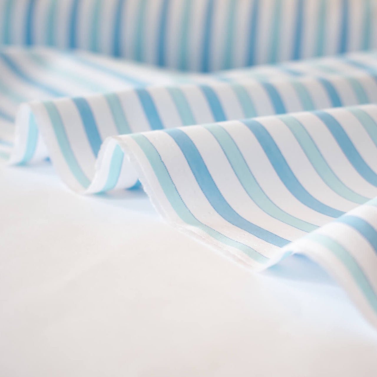 Designer striped cotton shirting that is soft, silky and "Fresh as Air"!  White, powder blue and sky blue woven vertical stripes will bring a freshness to your style.  Perfect for summer dresses, the classic shirtdress, a classic tailored shirt, or tunic. Image of selvedge.