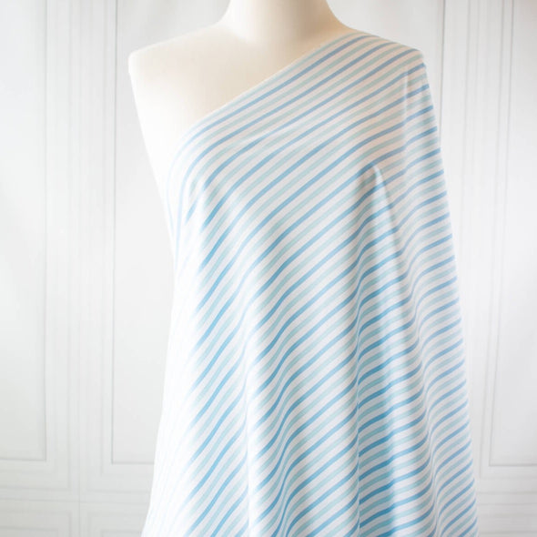 Designer striped cotton shirting that is soft, silky and "Fresh as Air"! White, powder blue and sky blue woven vertical stripes will bring a freshness to your style. Perfect for summer dresses, the classic shirtdress, a classic tailored shirt, or tunic. Image of fabric draped on dress form.