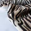 Famous Designer Rayon Challis flowy and soft animal print in tan white and black. Photo depicts fabric edge