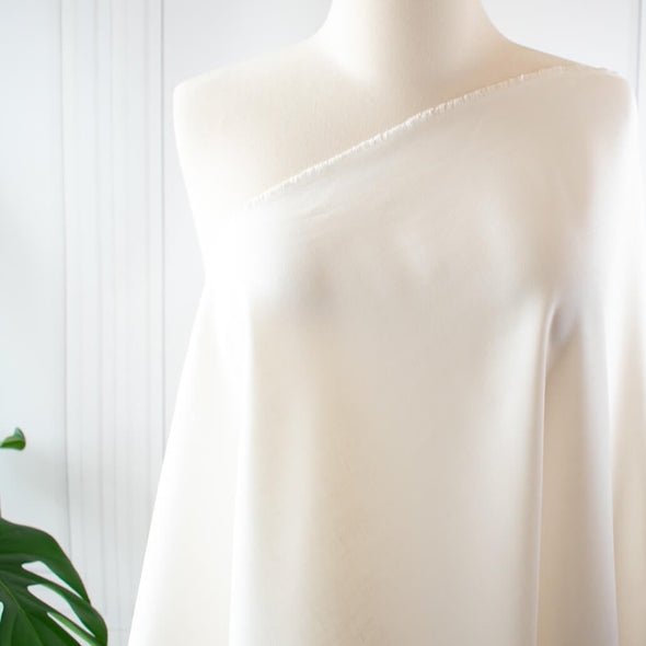 From a designer known for sophisticated and minimalist designs, you'll fall in love with this absolutely stunning Italian linen blend in a soft pearly white.   Slightly crisp with a soft hand and on the lighter side of a mid-weight. Perfect for more tailored garments... maybe a summer sundress! Image of fabric draped on dress form.