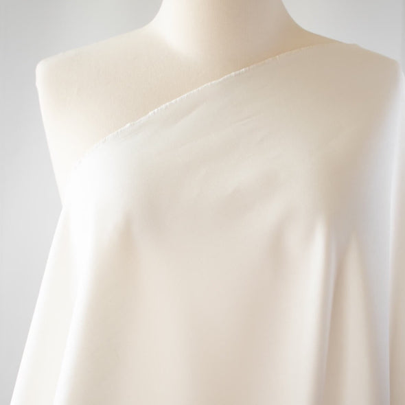 From a designer known for sophisticated and minimalist designs, you'll fall in love with this absolutely stunning Italian linen blend in a soft pearly white.   Slightly crisp with a soft hand and on the lighter side of a mid-weight. Perfect for more tailored garments... maybe a summer sundress! Image of fabric on dress form close up