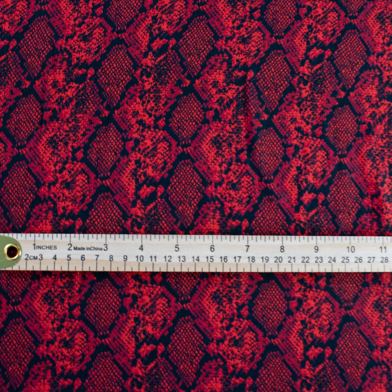 Whip yourself a stunning dress or top in this sophisticated designer deadstock animal print with a stunning red background. Photo of fabric design with ruler to demonstrate scale of animal print pattern.