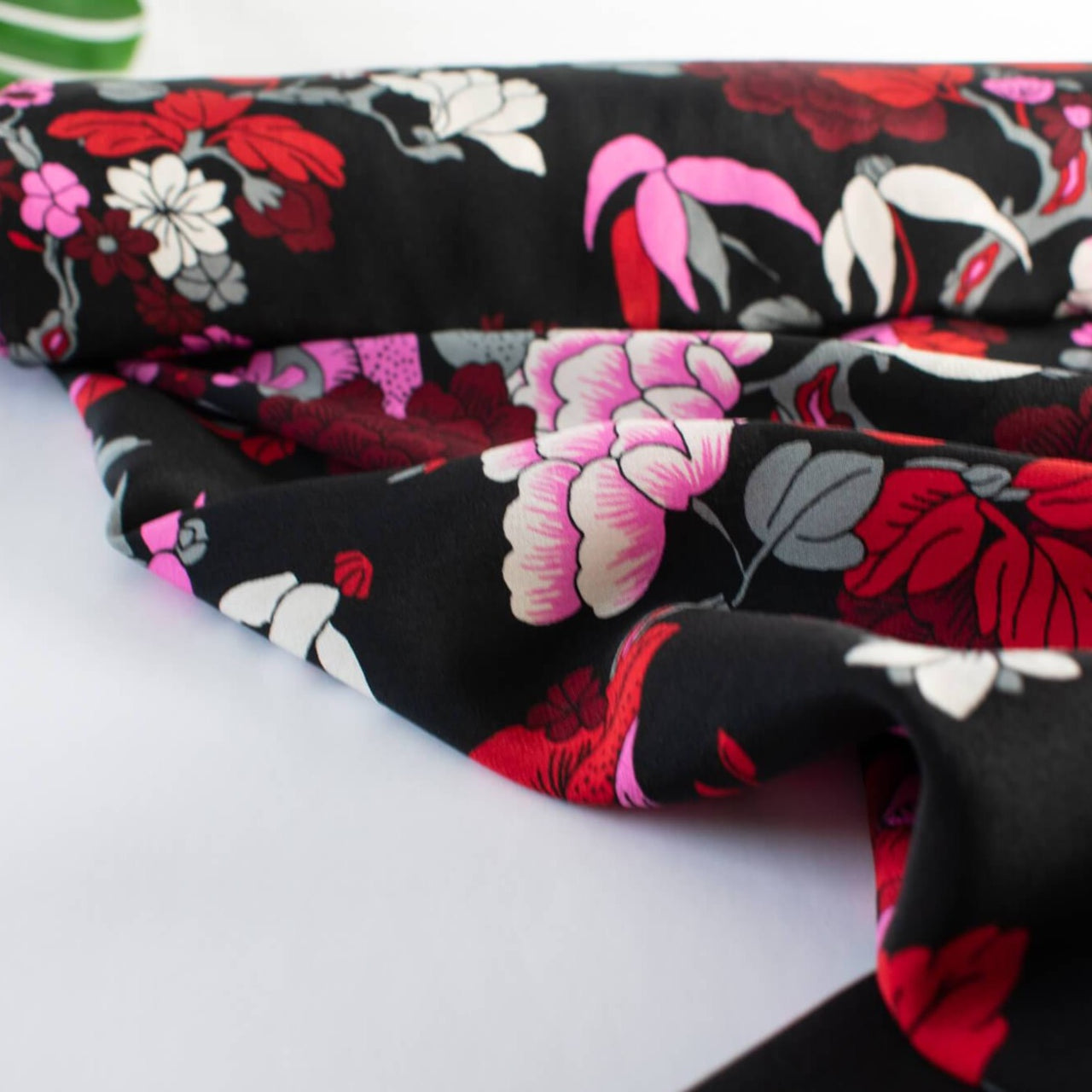 Create something stunning with this Designer Silk Crepe de Chine in florals of pinks, red, white, burgundy and grey upon a black background. Photo depicts fabric body.