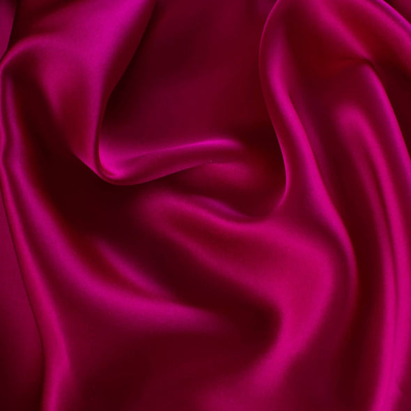 Simply stunning razzleberry pink charmeuse from a high end designer label 100% silk in a generous 52 inch width. Charmeuse is a popular fabric for creating fluid bias cut garments and luxurious lining to your special pieces like the French Jacket. Closeup photo.
