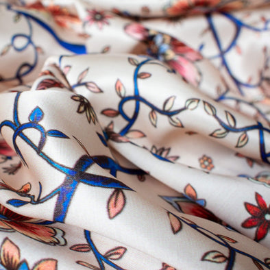 Silky rayon floral jacobean print . A vine in a gorgeous shade of electric blue trails through florals of various shades of peach, red and blue. Close uo photo.