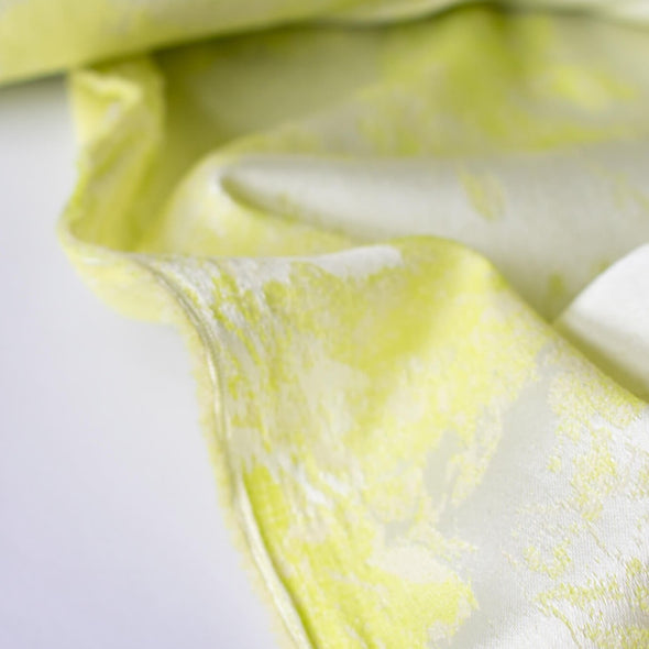 designer stretch floral jacquard fabric in lime green and white. Create a statement piece with this stunning fabric. Image is of selvedge edge.