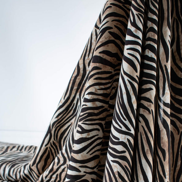 Famous Designer Rayon Challis flowy and soft animal print in tan white and black. Photo depicts fabric drape.  
