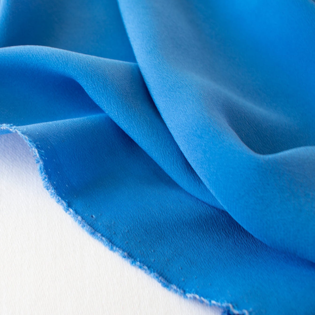 The soft, semi-textured fluid drape of this stunning French blue crepe will create a lovely dress or top.  Image of selvedge edge.