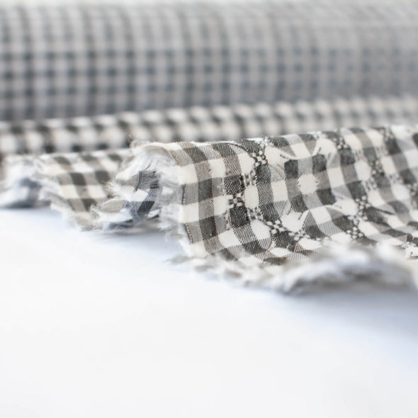 Gingham never looked so good!  Designer, black and white stretch woven has a dobby weave creating a geometric pattern which transforms the fabric into something truly special. This fabric has bit of a vintage vibe and is soft with a textured pattern and stretch along the selvedge.   image of selvedge