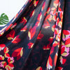 Tulip petals in red, ochre, pink and maroon float above off black daisies in a rich background of aubergine. Floral viscose crepe from Italy has a lovely drape. Image of fabric drape.