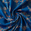 A stunning blue rayon floral challis will have you dreaming of summer strolls, taking in the sunshine and feeling so fine.  Soft and airy, perfect for lazy day dresses, billowy tops, or a simple cami and skirt.    Trailing light grey daises and red flowers with light turquoise leaves trail a delicate path against a medium blue background.   Image of fabric body.