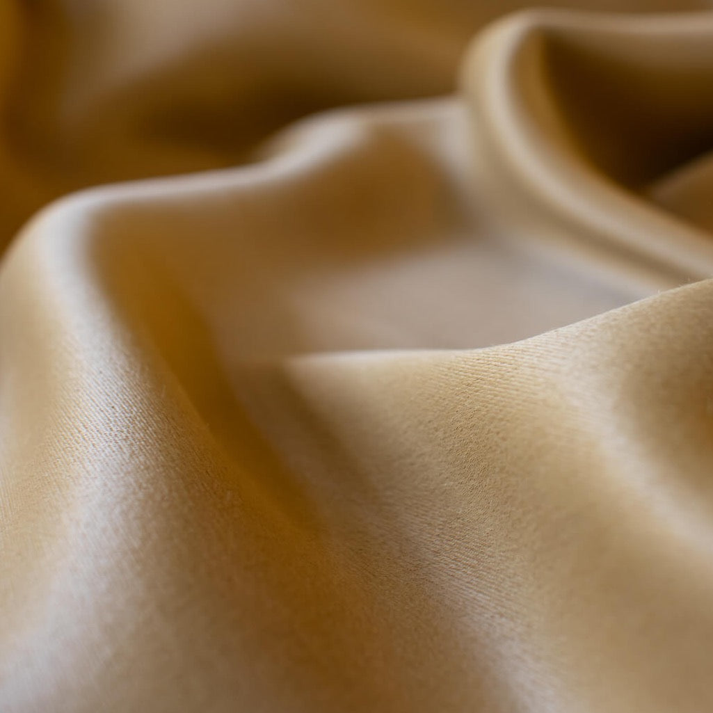 Enjoy a bit of 'Old Hollywood Glamour' in this dark gold stretch crepe back satin from a LA Designer. This satin is soft with a smooth hand and gorgeous sheen on the face side and a textured hand on the crepe back.  Bring out your inner designer and use both sides of the fabric to create something special.   Close up image.