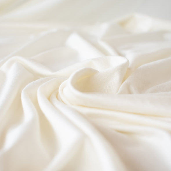 Casual and elegant, perfect for the popular flowy cardigan or wide leg pant.  Off white tissue jersey knit that is soft and flowy. Very thin hand, light and translucent from a Los Angeles designer. close up image of fabric fluidity and flow.