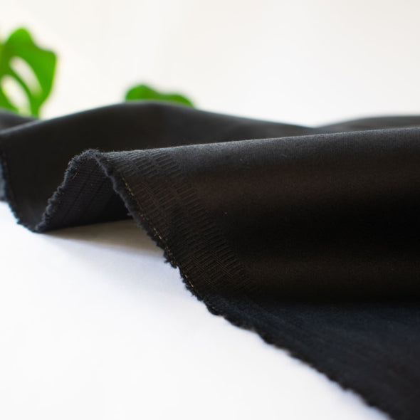 The lustrous sheen in this famous dress designer stretch sateen is a sure standout. In matte black, it has a smooth thin hand and will sew up a perfect year round garment. Opaque and a bit of stretch, not only will you look stunning but it's comfortable too! Image of selvedge.