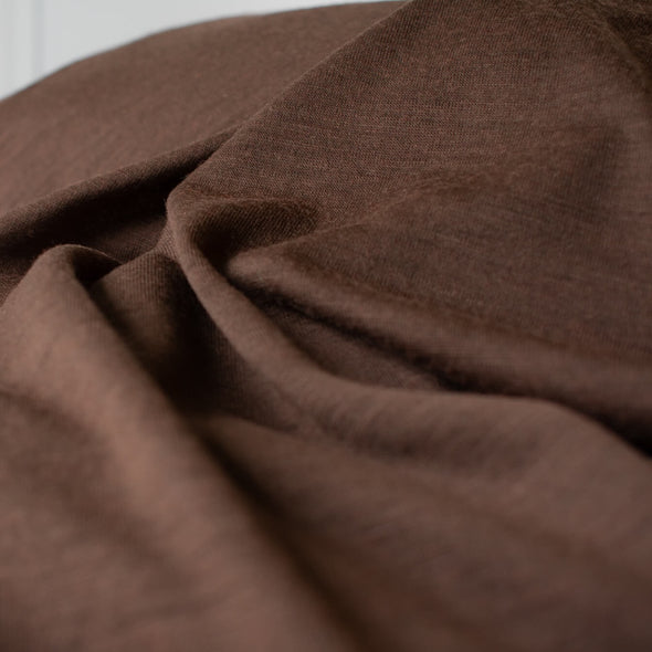 Merino Wool Jersey knit in a gorgeous chocolate brown.   This fabric has a soft hand and is light and flowy, perfect for a top or cardigan. It makes a perfect layering piece. A generous width at 63 inches and a mechanical stretch.  Close up image. 
