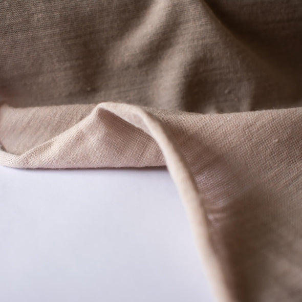 Merino Wool Jersey knit in a gorgeous truffle color.   This fabric has a soft hand and is light and flowy, perfect for a top or cardigan. It makes a perfect layering piece. A generous width at 55 inches and a mechanical stretch.  Image of selvedge edge.