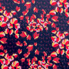 Tulip petals in red, ochre, pink and maroon float above off black daisies in a rich background of aubergine. Floral viscose crepe from Italy has a lovely drape. Image of fabric pattern.