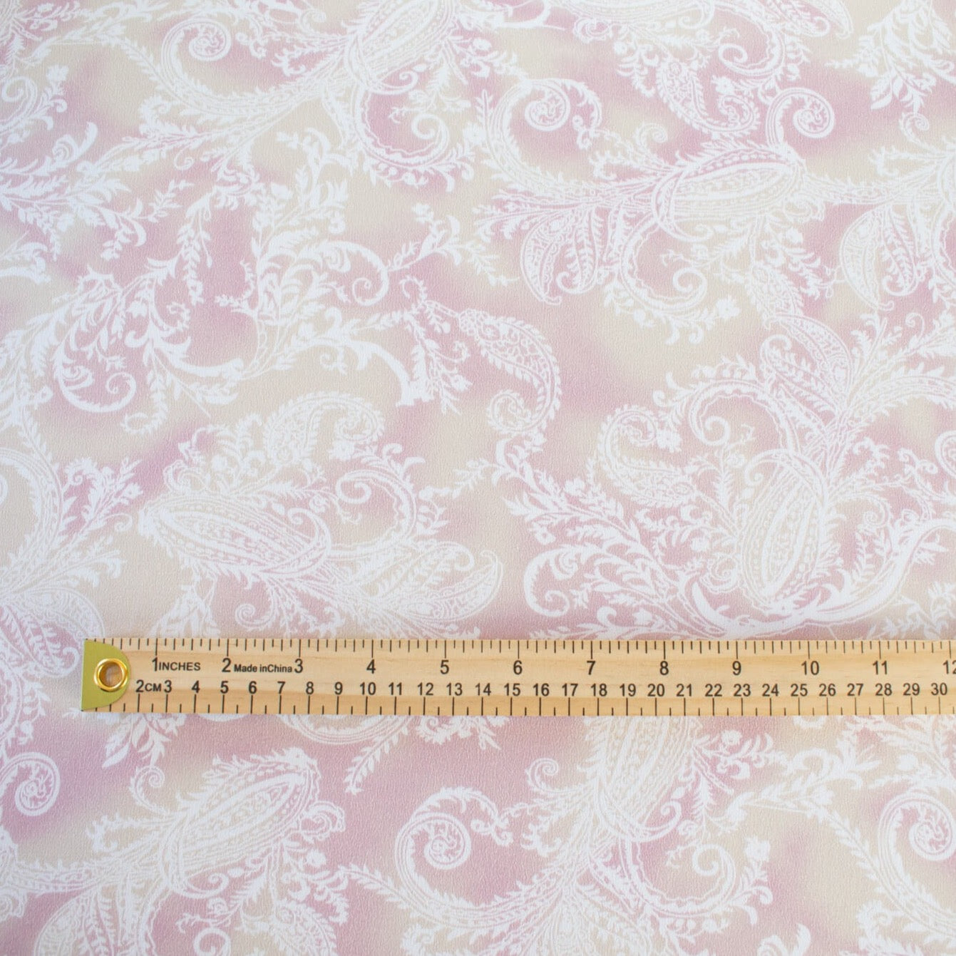 The soft pale rose and cream background with a white paisley print gives it a hint of 'Boho' vibe that's so L.A.    You'll look gorgeous in one of the popular flowy dresses or pants.  Or, if you prefer a sleeker look, this is a bias cut slip dress waiting to happen. Image of fabric with ruler for scale.