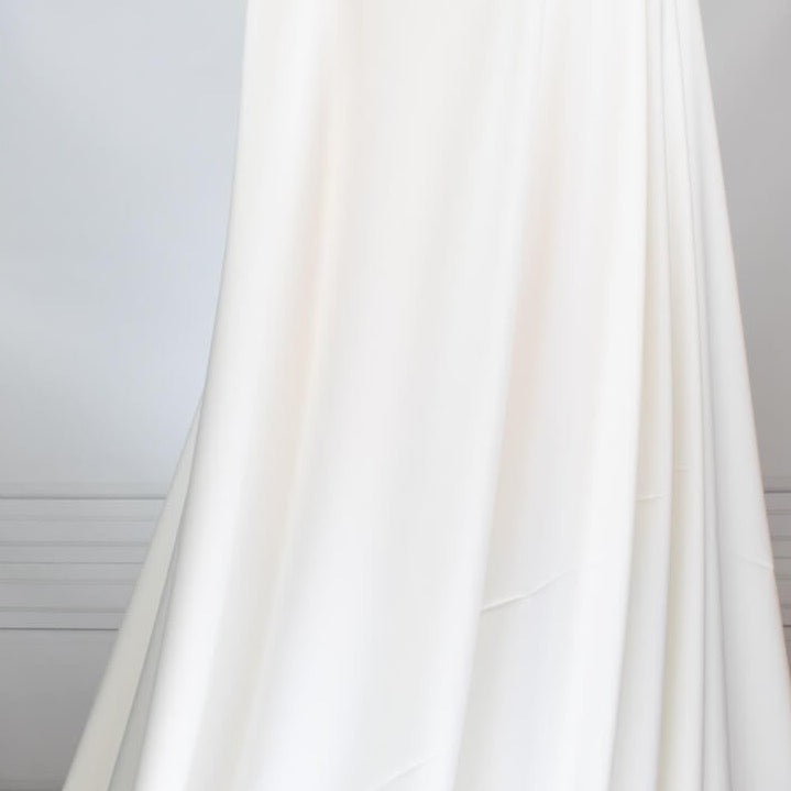 Power Suiting never felt so good!  NYC designer fine twill is a soft touch with a semi-textured hand. Not only is it in an easy to care for poly/lycra blend but it has a bit of stretch for comfort. This fine suiting is an opaque soft powder white that flatters!   Image of draped fabric.