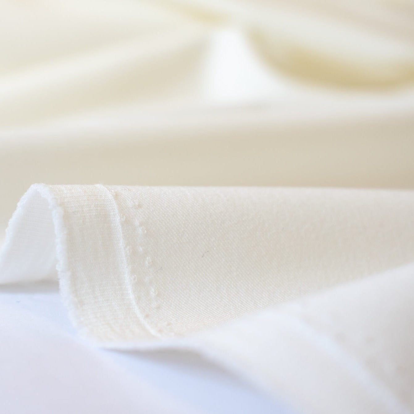 Power Suiting never felt so good!  NYC designer fine twill is a soft touch with a semi-textured hand. Not only is it in an easy to care for poly/lycra blend but it has a bit of stretch for comfort. This fine suiting is an opaque soft powder white that flatters!   Close up of selvedge edge.