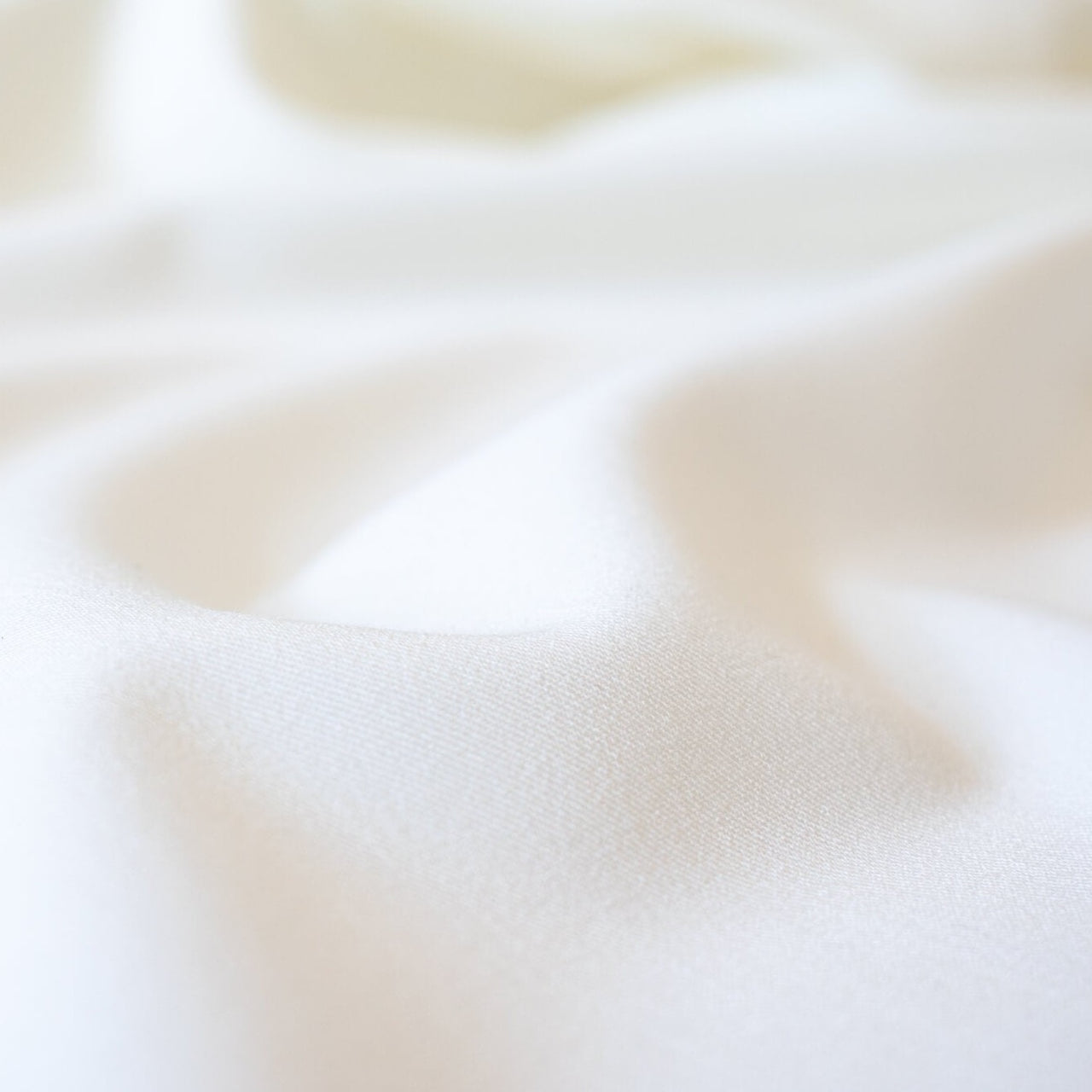 Power Suiting never felt so good!  NYC designer fine twill is a soft touch with a semi-textured hand. Not only is it in an easy to care for poly/lycra blend but it has a bit of stretch for comfort. This fine suiting is an opaque soft powder white that flatters!   Close up image