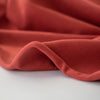 NY Designer cotton/lycra jersey in a warm scarlett red is super soft and super wide!  It is on the lighter side of a mid-weight and has excellent stretch and recovery. A cotton knit with lycra is perfect for sewing up a gorgeous top for warmer weather! Image of fabric selvedge.