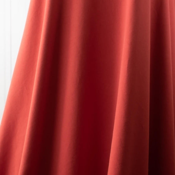 NY Designer cotton/lycra jersey in a warm scarlett red is super soft and super wide!  It is on the lighter side of a mid-weight and has excellent stretch and recovery. A cotton knit with lycra is perfect for sewing up a gorgeous top for warmer weather! Image of fabric drape.