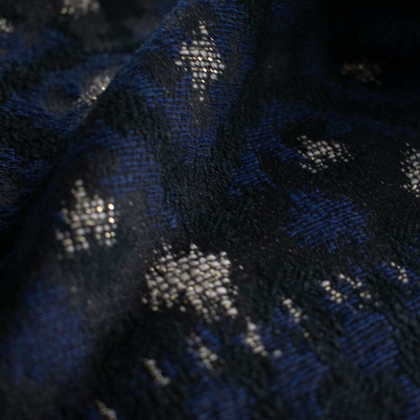 The golden metallic threads of this Italian jacquard create a diamond pattern, bordered in a black diamond shape that is just stunning.  A soft textured hand and medium weight make it perfect for a stylish jacket!  close up image